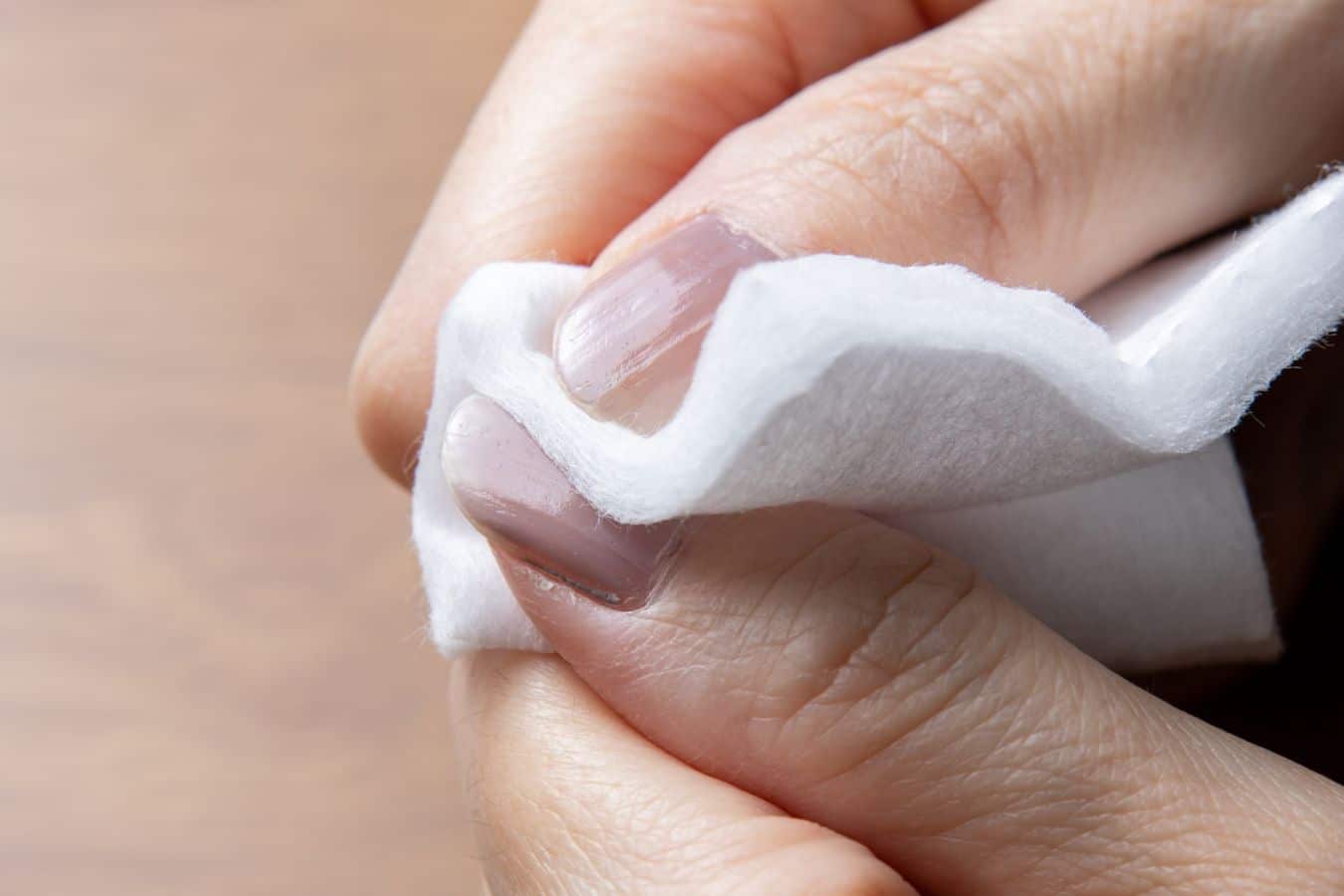 Person removing nail polish from a fingernail to inspect the natural nail for changes that could indicate nail melanoma.