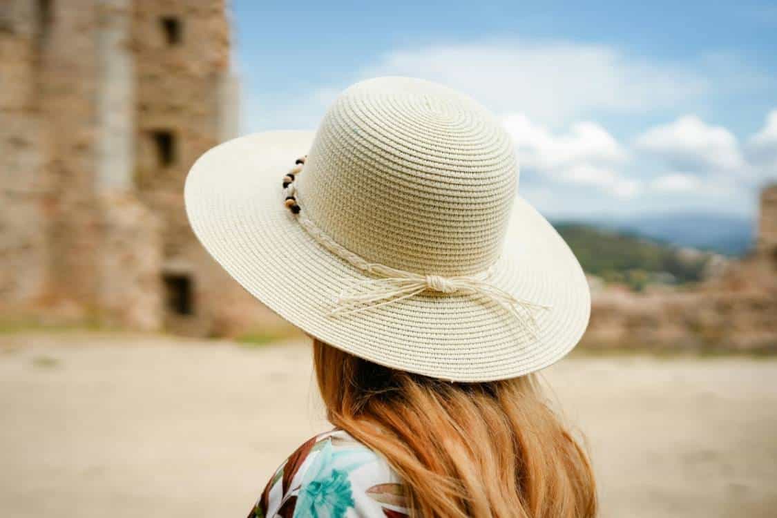 Person wearing a wide-brimmed sun hat outdoors to help protect the skin from UV exposure and reduce the risk of melanoma and other skin cancers.